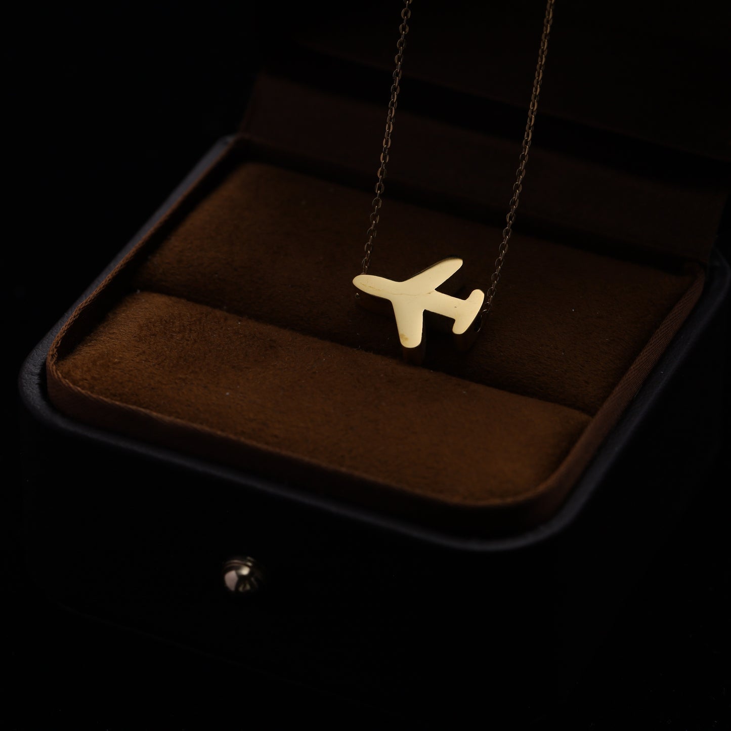 Close-up of a gold-plated airplane pendant on an adjustable sliding chain.