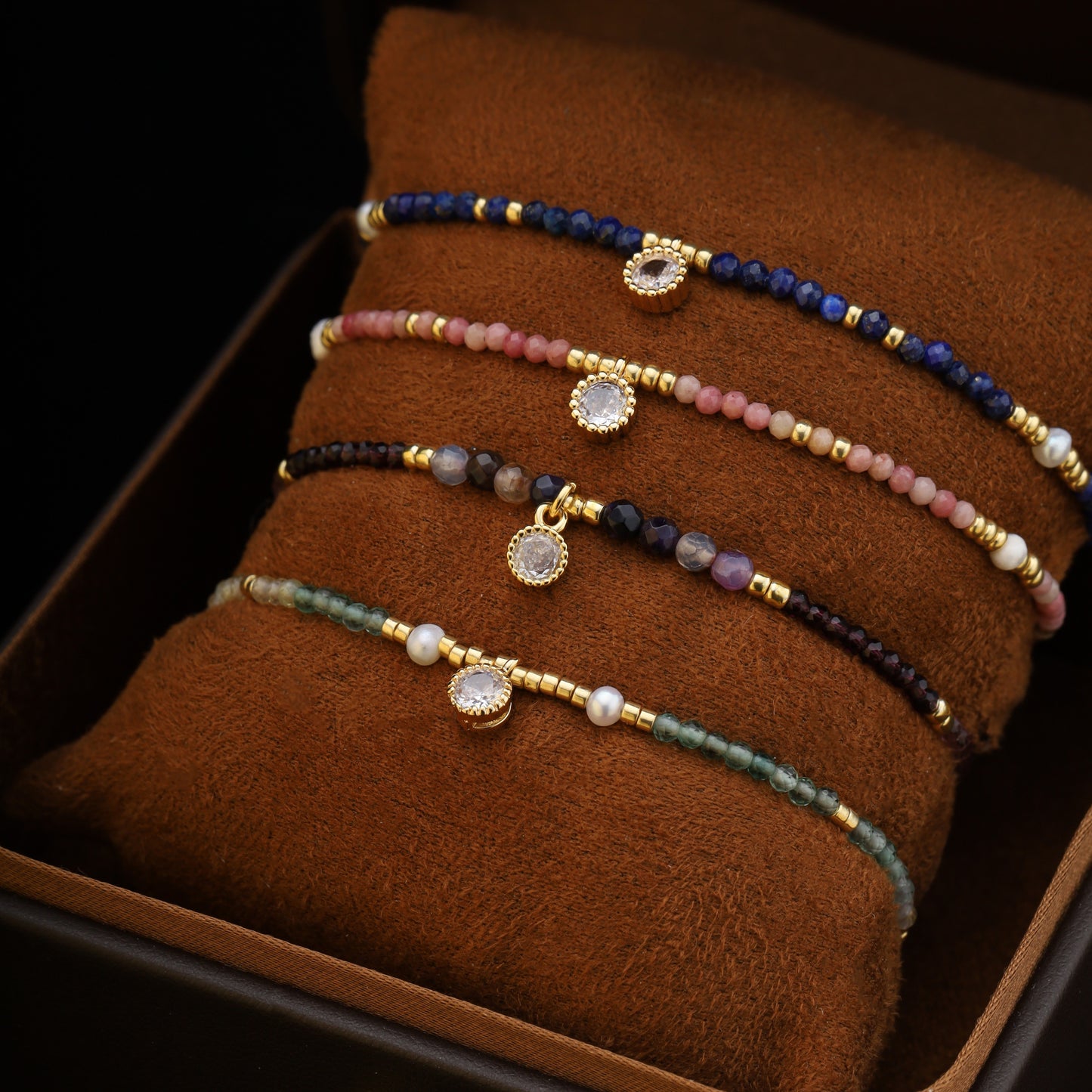 A set of 4 gemstone and pearl beaded bracelets stacked in a box, showcasing different color options.