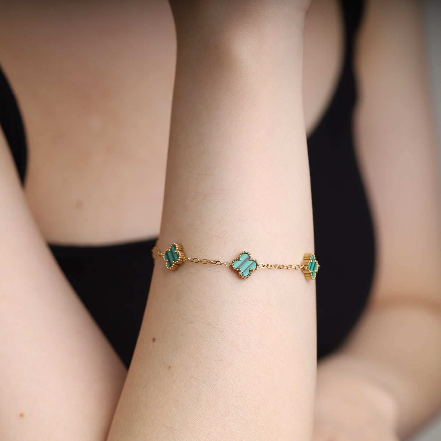 Gold-tone stainless steel bracelet with malachite clover-shaped charms