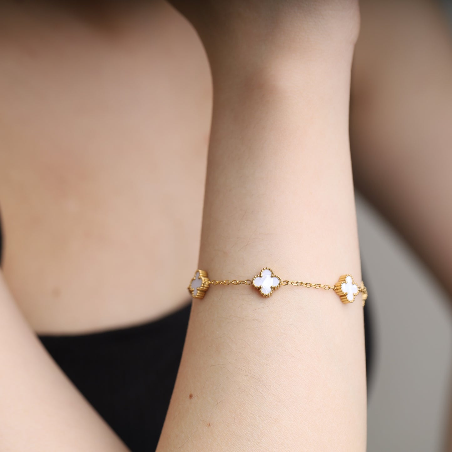 Gold-tone bracelet with white clover-shaped charms
