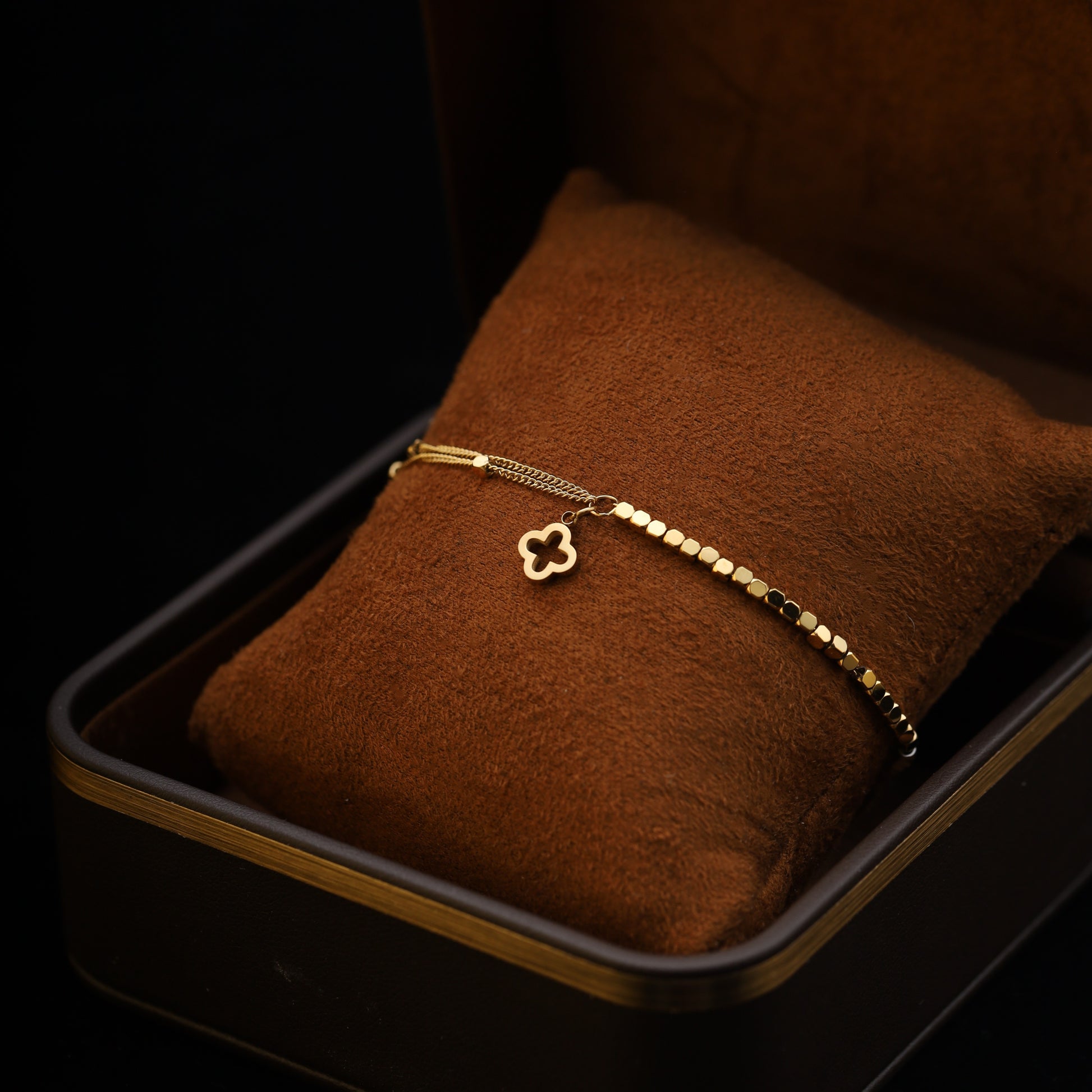 – Side angle of bracelet wrapped around brown cushion with charm visible.