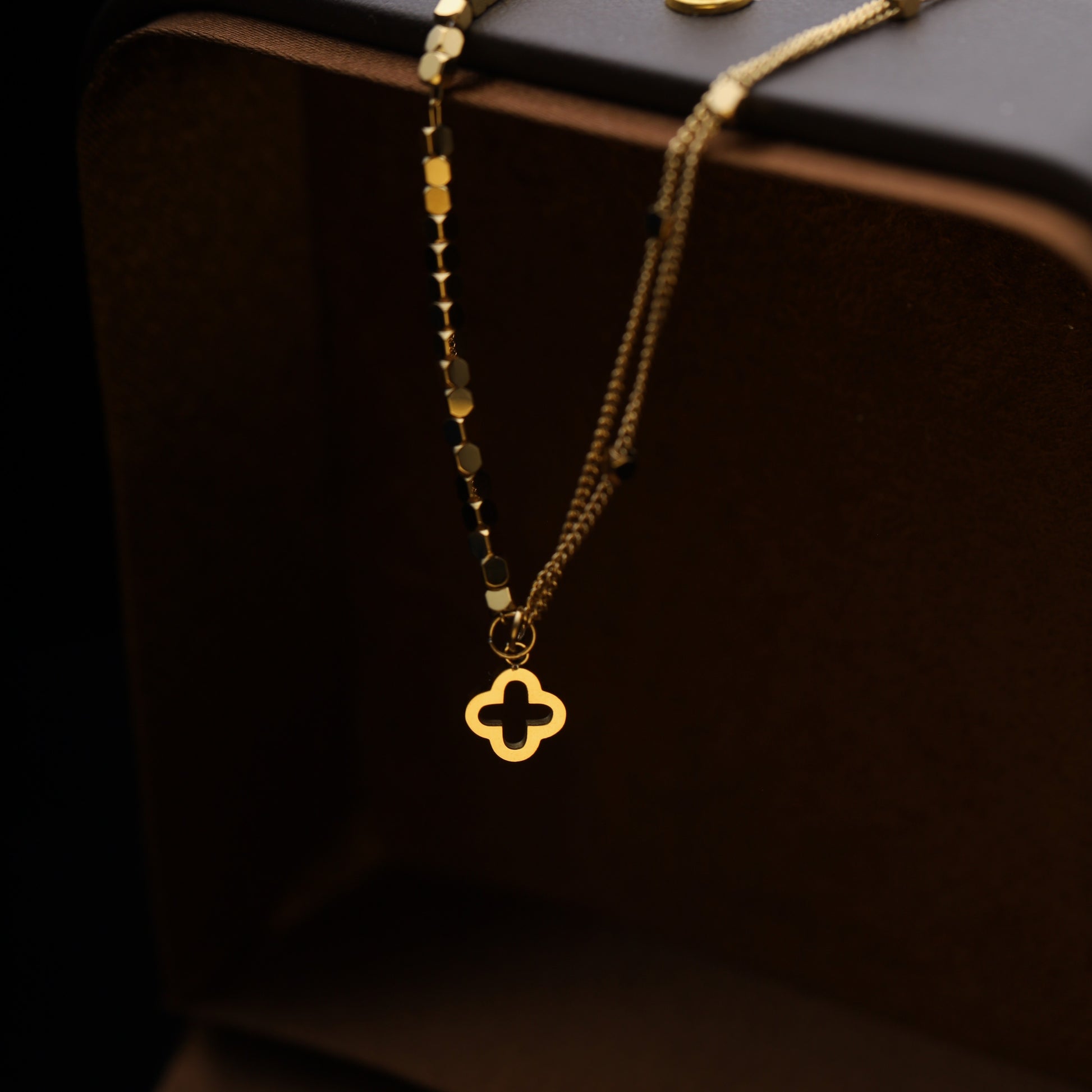 Detail view of the clover charm and double chain hanging from edge.