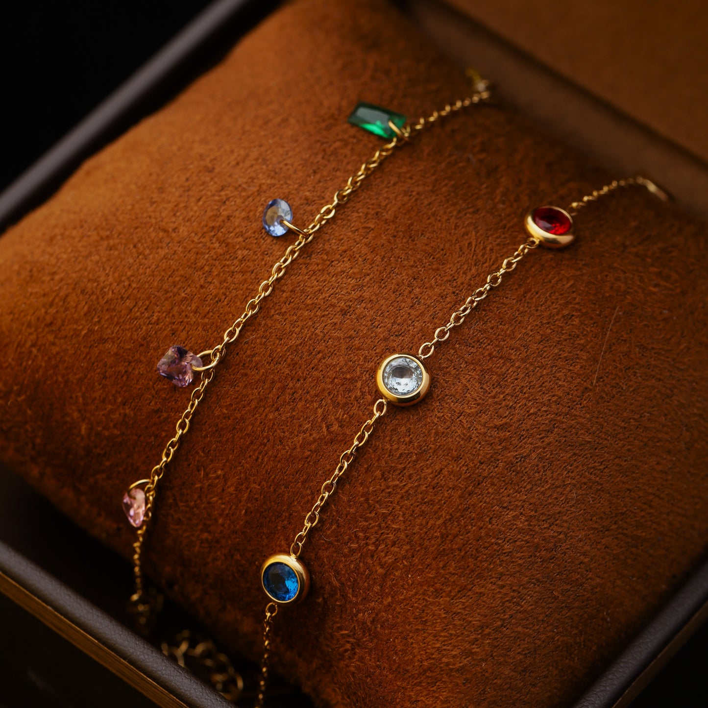 Close-up of bracelet layering with bezel-set rainbow bracelet