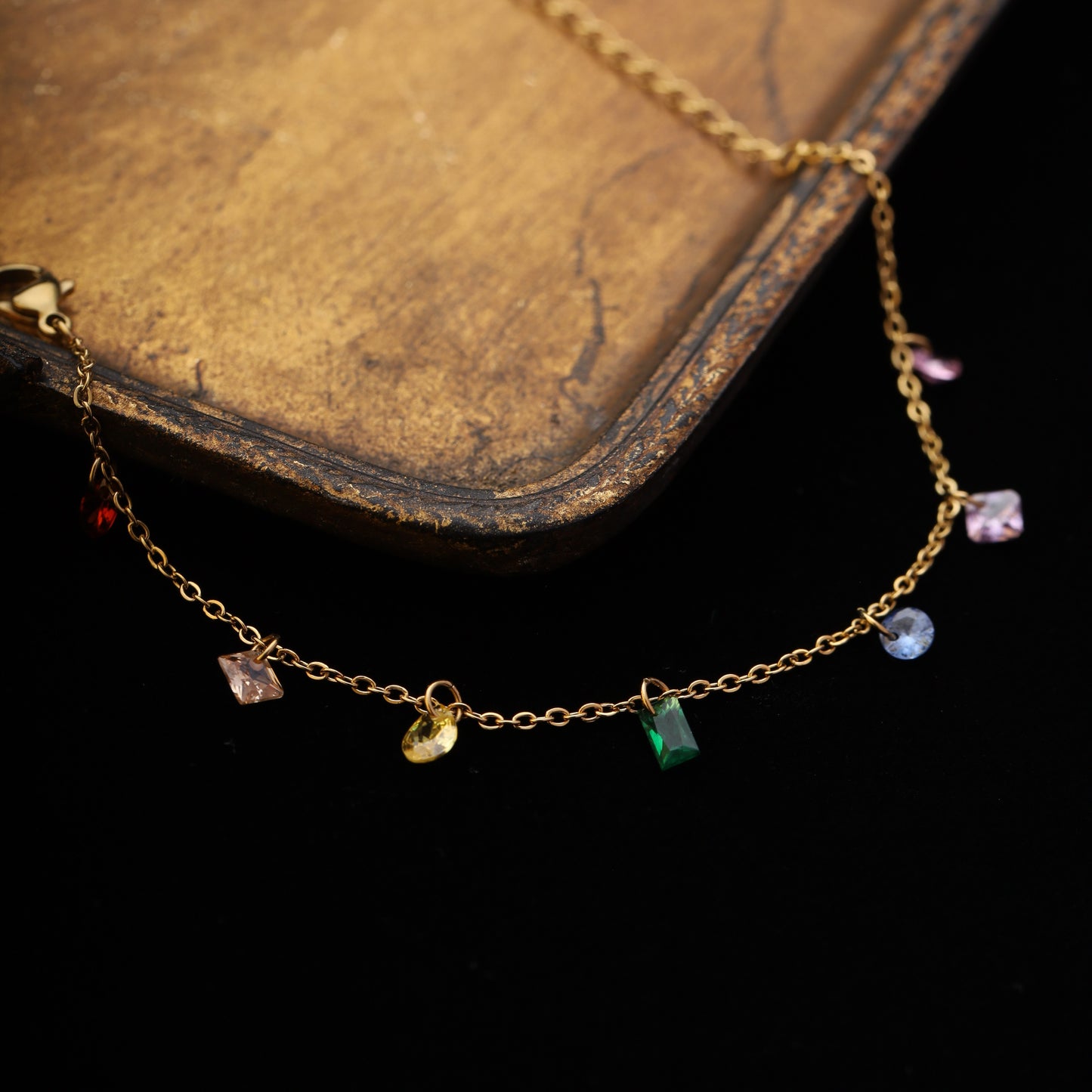 Dangling crystal bracelet draped over gold tray