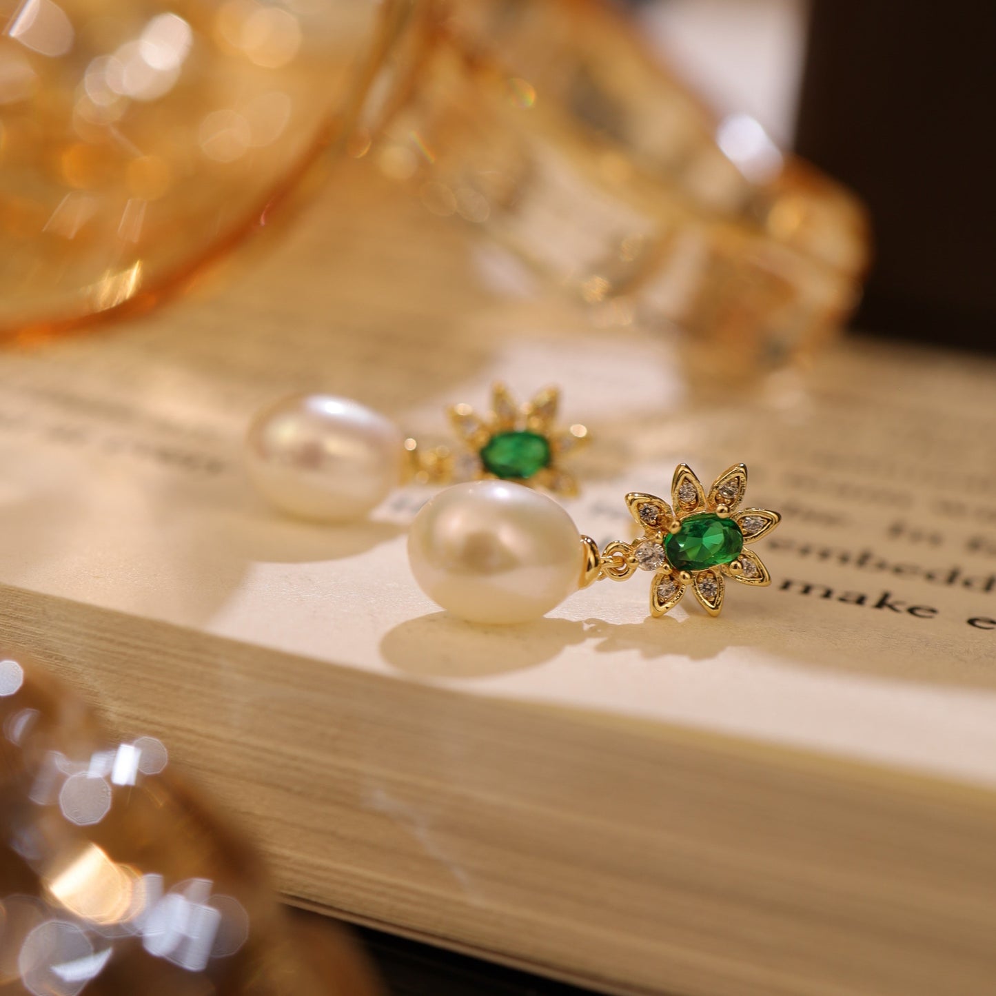 A pair of emerald green freshwater pearl earrings displayed elegantly on an open book.