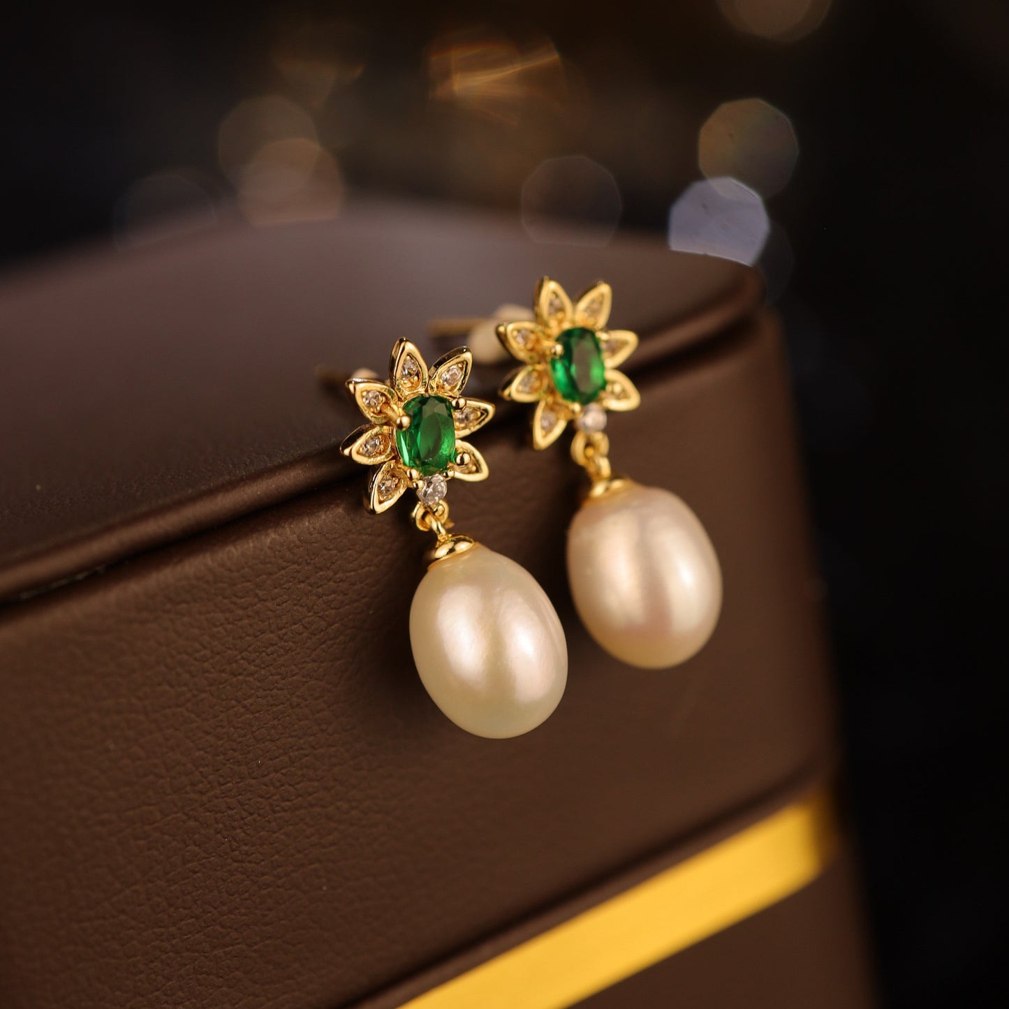 A close-up of emerald green freshwater pearl earrings resting on a jewelry box, showcasing their elegant details.