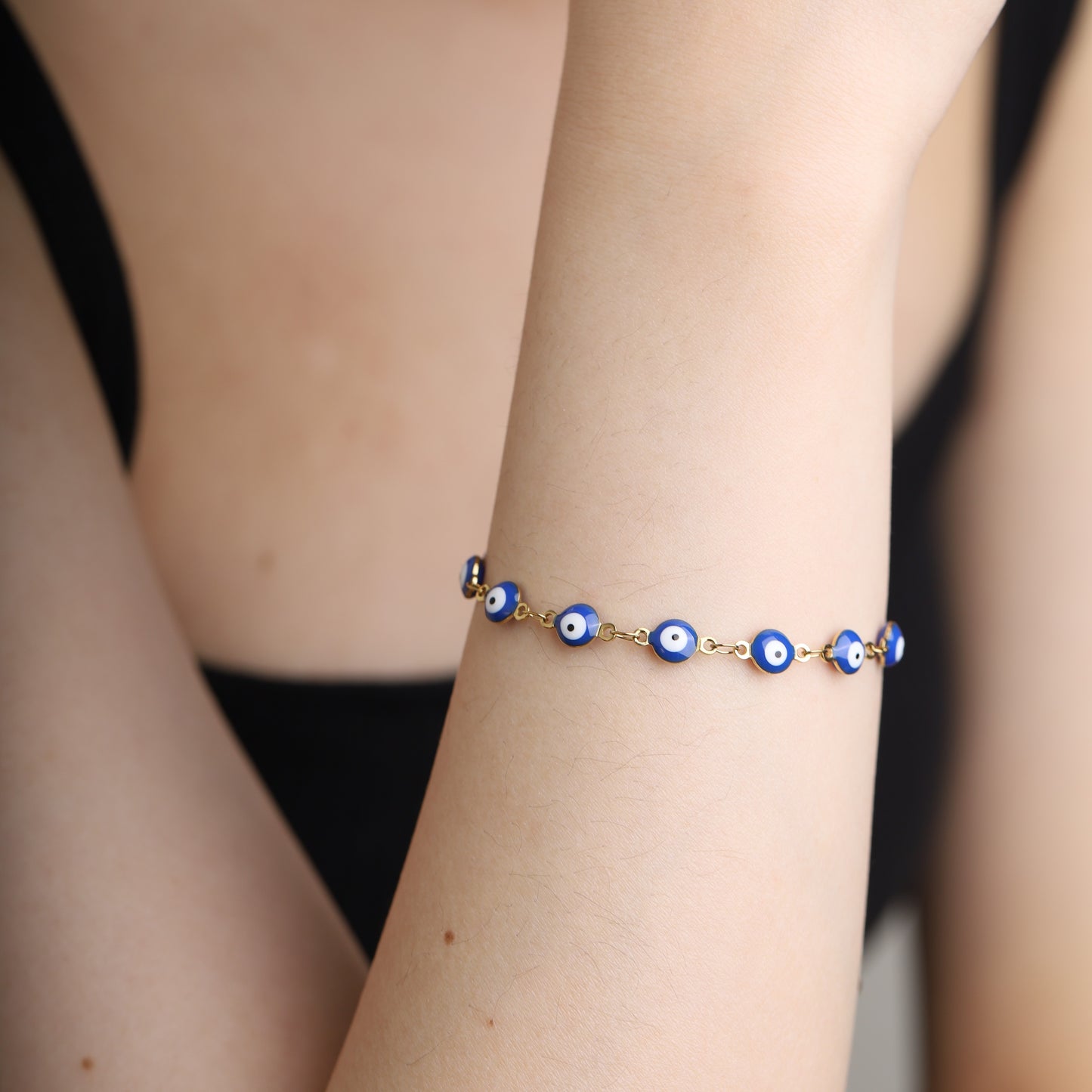 Blue evil eye bracelet with gold chain worn on wrist