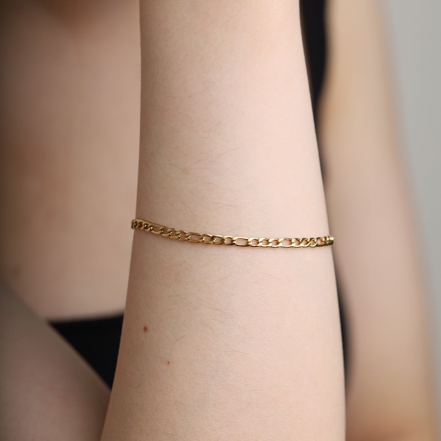 Gold Figaro bracelet styled on wrist.