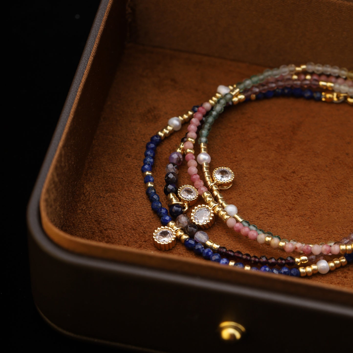 Overhead shot of colorful gemstone and pearl beaded bracelets layered together.