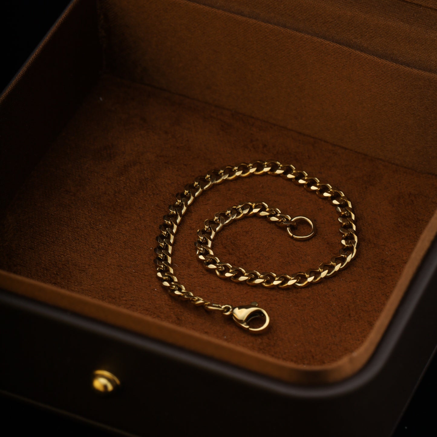 Top-down shot of 4mm gold bracelet curled in a circle inside a jewelry box