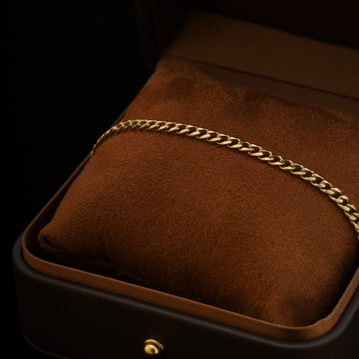 4mm gold Cuban chain bracelet styled on a brown suede cushion