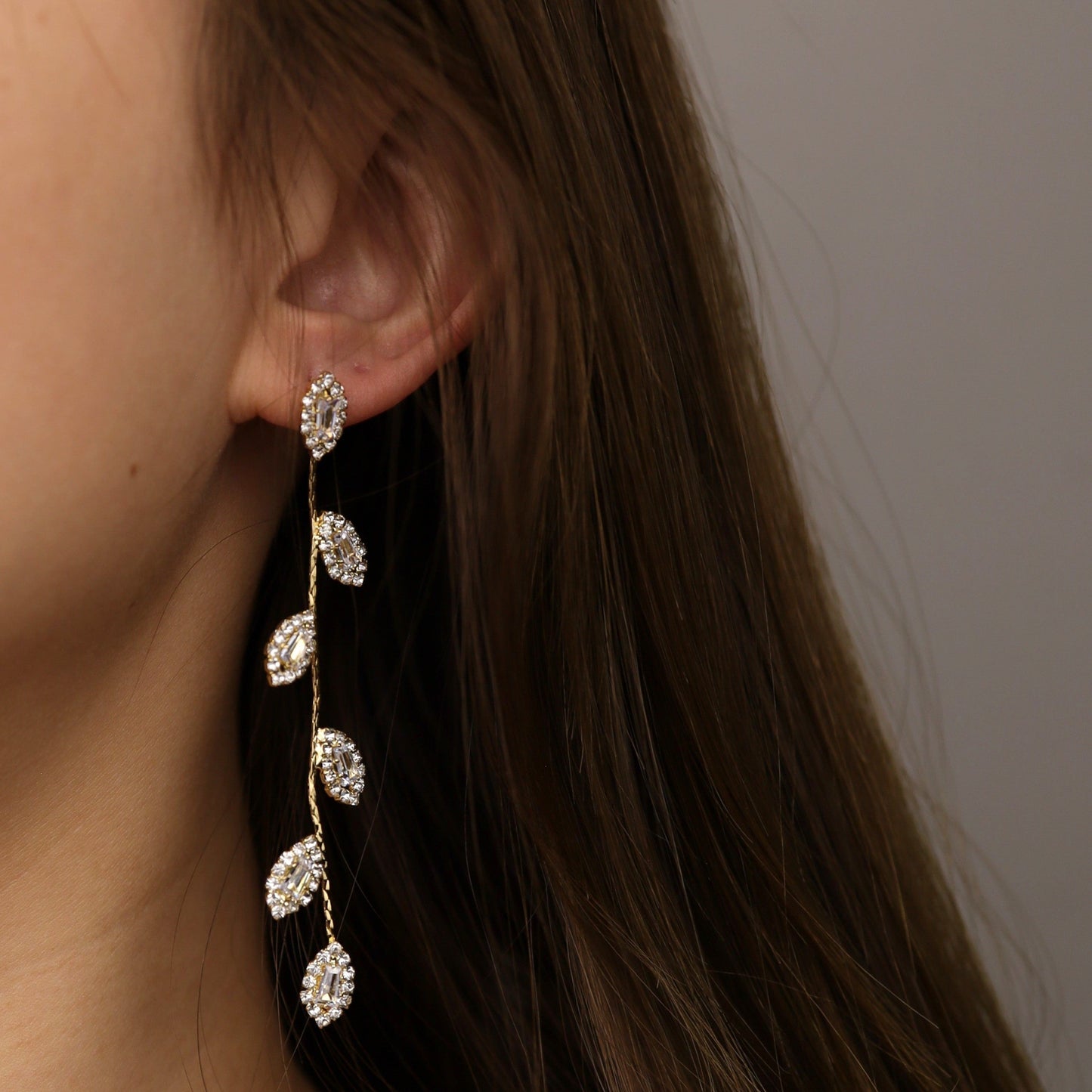 A pair of elegant leaf-inspired dangle earrings worn on a model, showcasing their graceful movement.