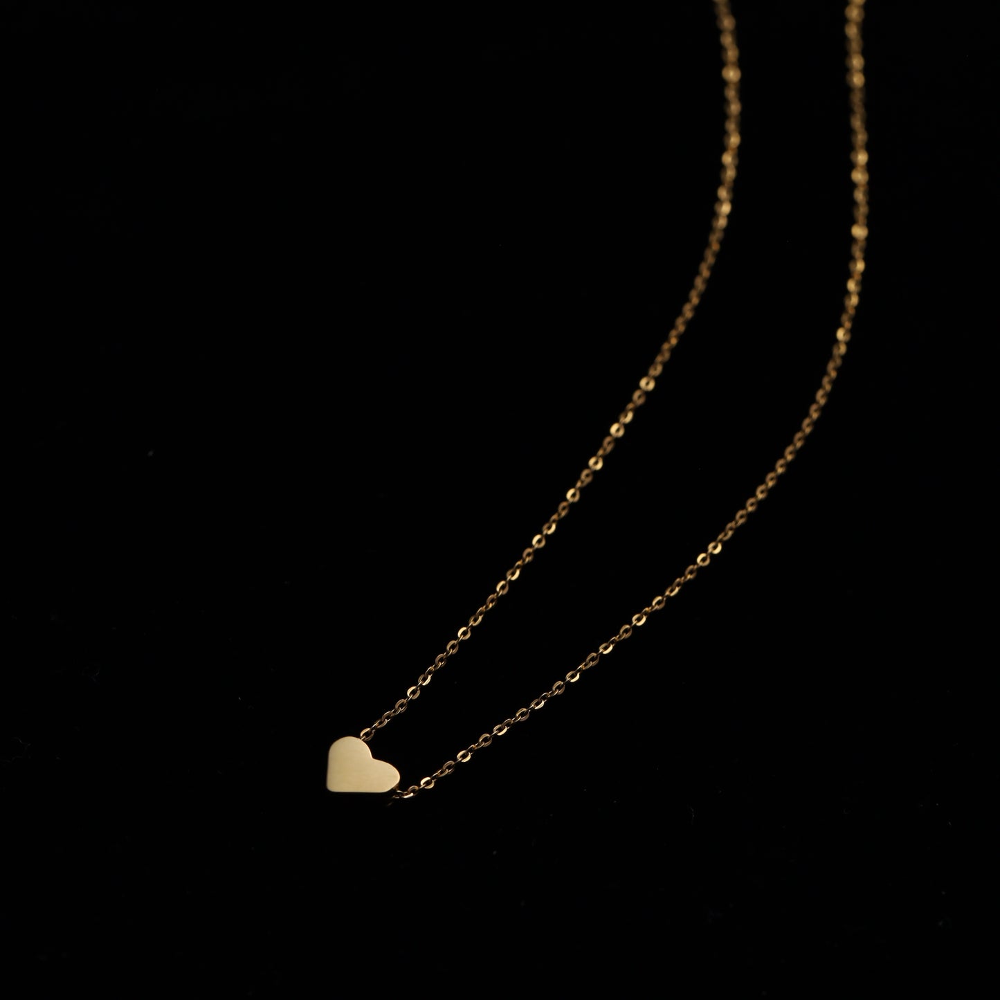Gold stainless steel heart necklace with an adjustable sliding chain on a black background.