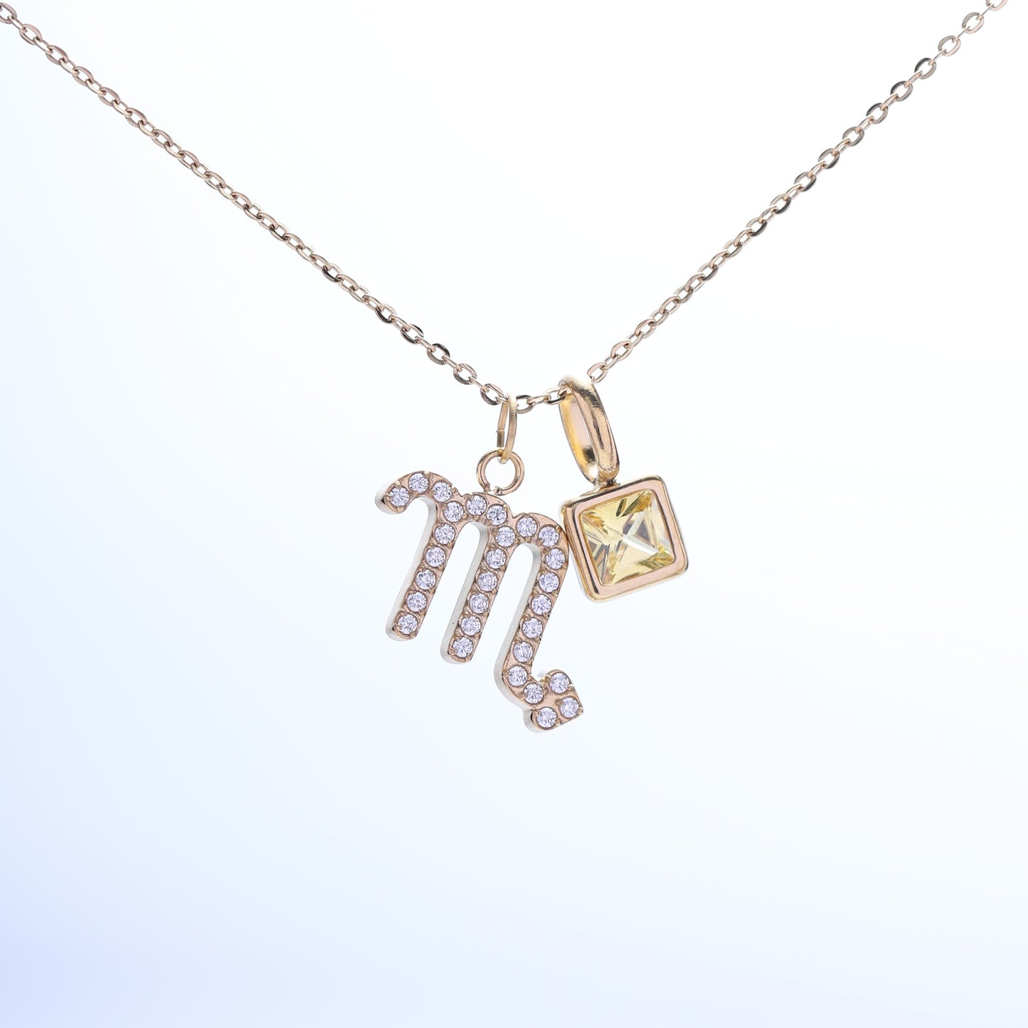 A gold-plated Scorpio zodiac necklace with white background