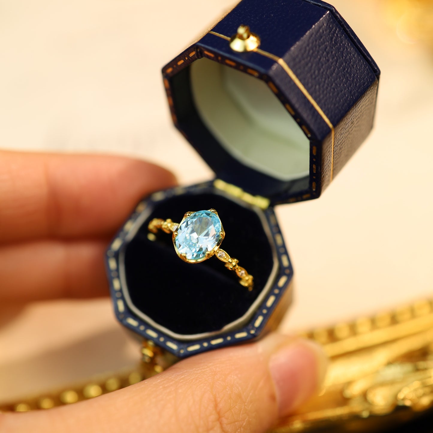 A sterling silver blue gemstone ring in a navy vintage jewelry box.