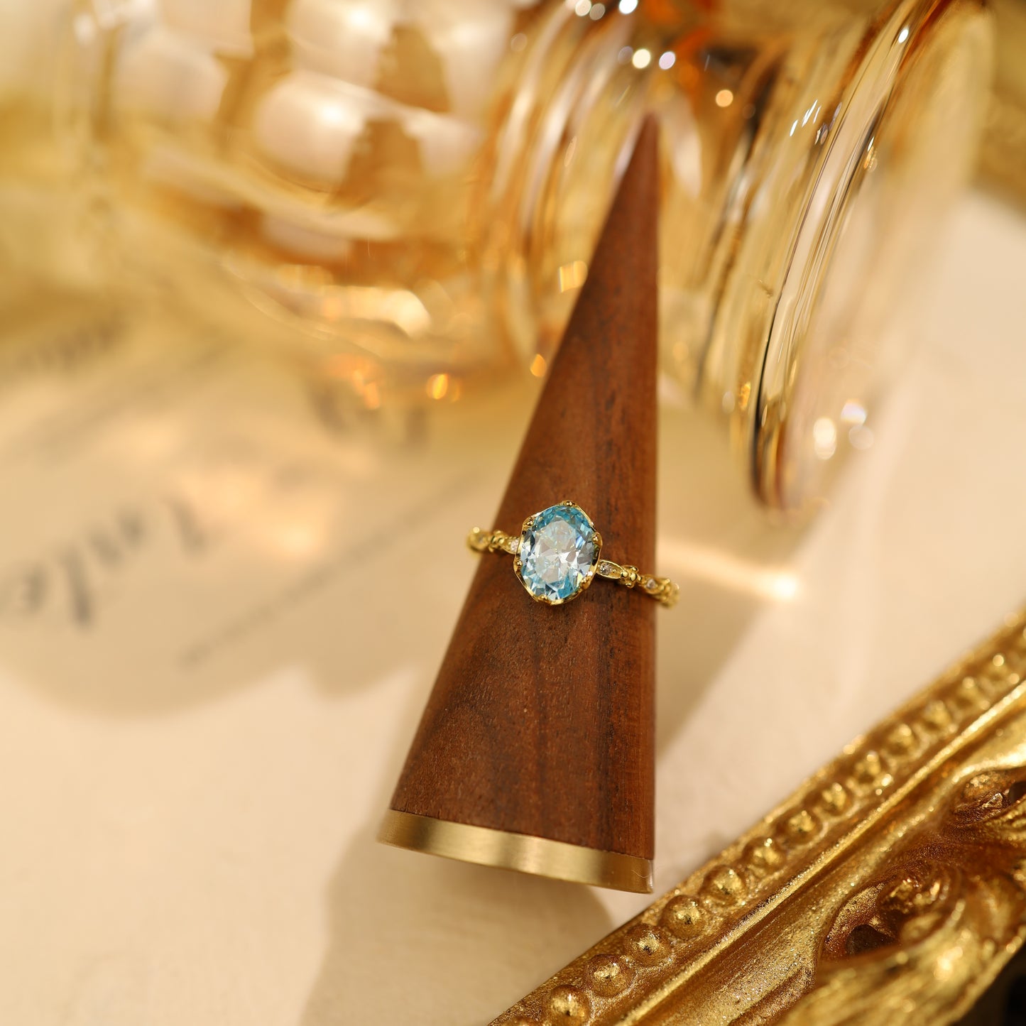 A classic shot of a sterling silver ring with a blue gemstone resting on a wooden ring holder.