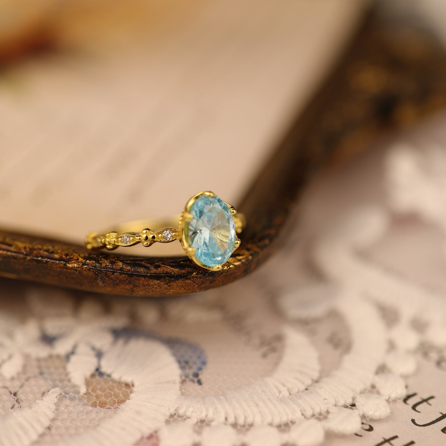 A delicate sterling silver ring with a blue gemstone, styled on lace with a vintage feel.