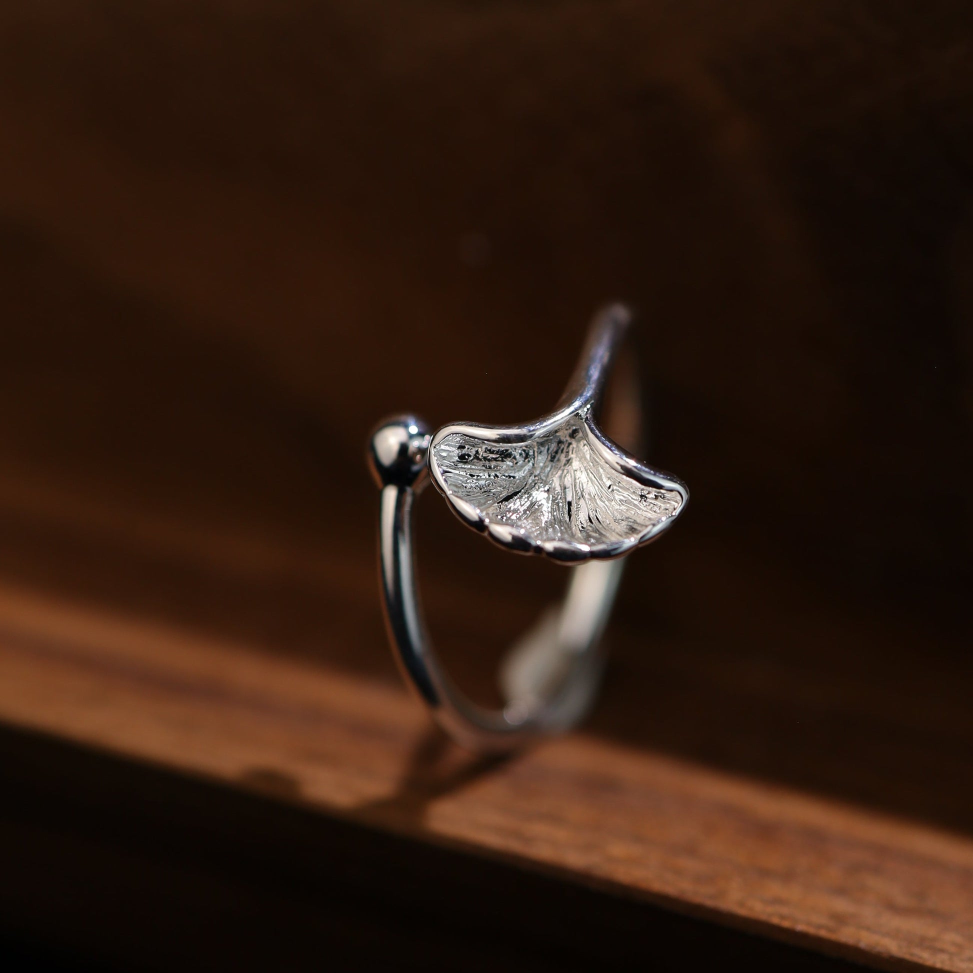 Front view of the sterling silver ginkgo leaf ring on a wood background.