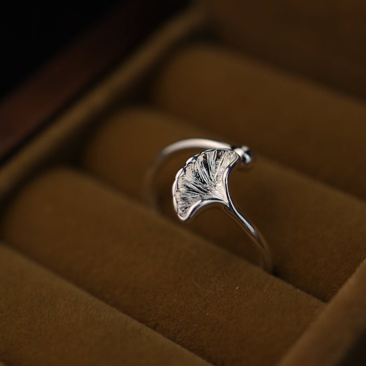 Sterling silver ginkgo leaf ring placed inside a brown velvet ring box.