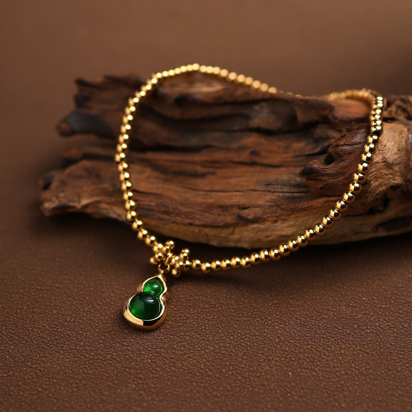 Green hulu charm bracelet hanging from driftwood